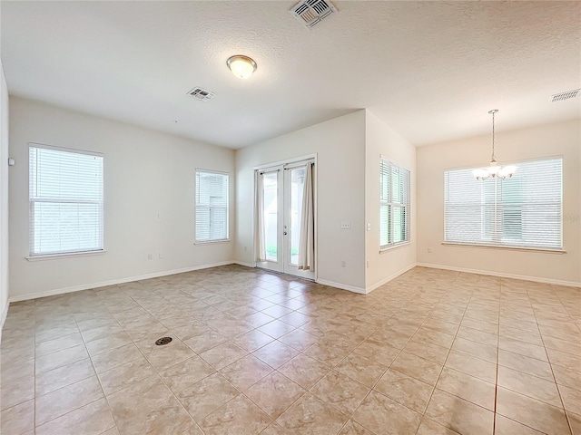 empty room with a wealth of natural light, visible vents, and an inviting chandelier