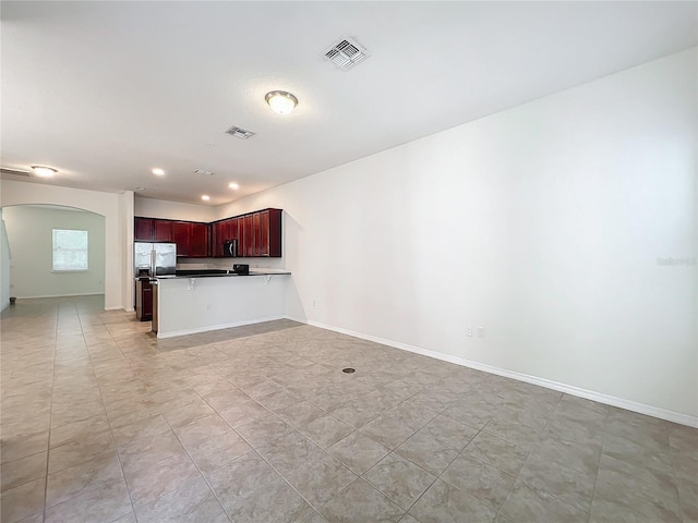 kitchen with stainless steel fridge, visible vents, arched walkways, open floor plan, and a peninsula