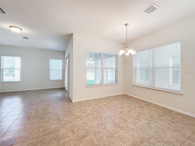 empty room with an inviting chandelier, baseboards, visible vents, and a textured ceiling