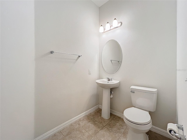 half bathroom with toilet, baseboards, and tile patterned floors