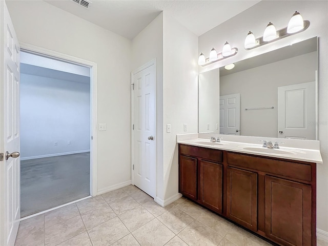 bathroom with double vanity, baseboards, a sink, and tile patterned floors