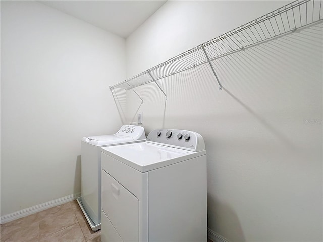 laundry room featuring laundry area, light tile patterned floors, baseboards, and washer and dryer