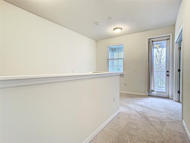 corridor featuring an upstairs landing, light carpet, and baseboards