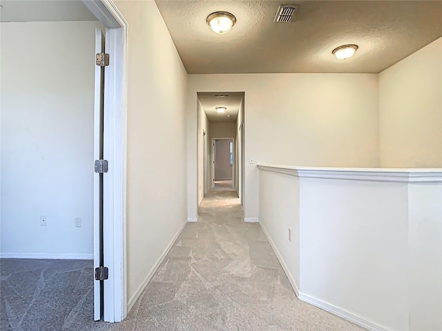 corridor with a textured ceiling, carpet floors, visible vents, and baseboards