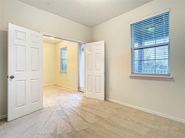 unfurnished bedroom with baseboards and light colored carpet