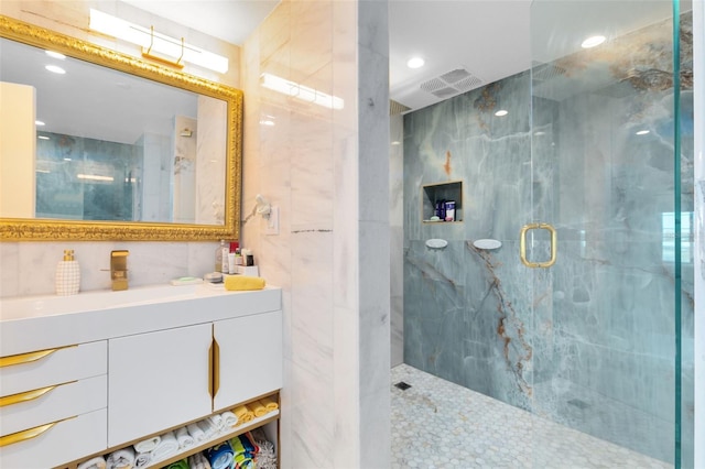 bathroom featuring vanity, walk in shower, and tile walls