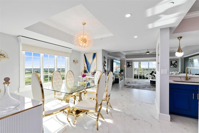 dining area featuring ceiling fan with notable chandelier, a raised ceiling, ornamental molding, and sink