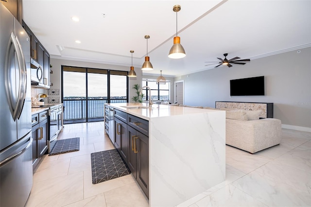 kitchen featuring appliances with stainless steel finishes, a wealth of natural light, hanging light fixtures, and a kitchen island with sink