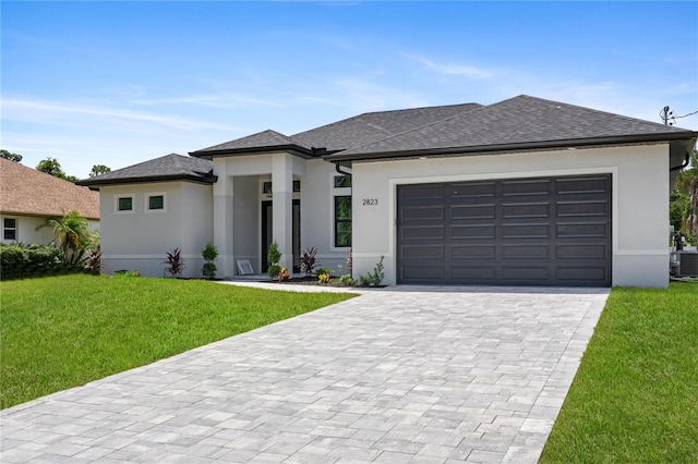 prairie-style house featuring a garage, central air condition unit, and a front lawn