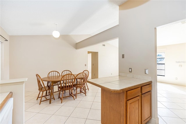 kitchen featuring tile counters, light tile patterned floors, and lofted ceiling