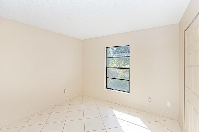 unfurnished room featuring a textured ceiling and light tile patterned flooring