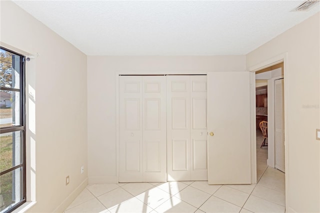 unfurnished bedroom with a textured ceiling, a closet, and light tile patterned flooring