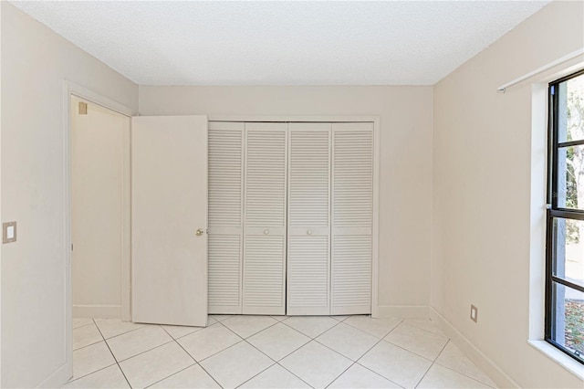 unfurnished bedroom with light tile patterned floors, a textured ceiling, and a closet