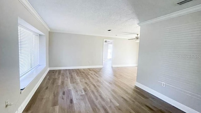 empty room with hardwood / wood-style flooring, crown molding, ceiling fan, and a textured ceiling