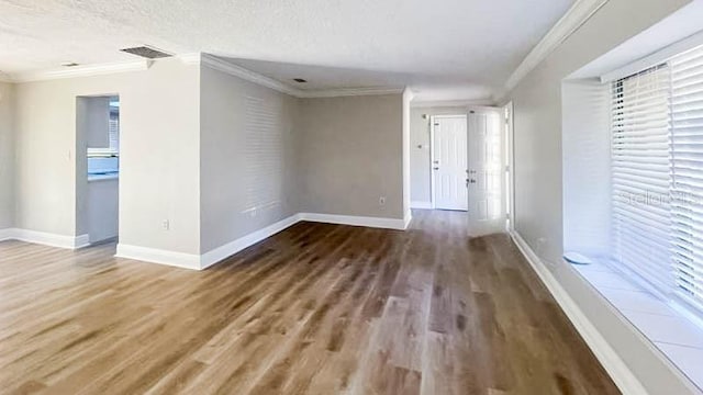 empty room featuring crown molding, wood-type flooring, and a textured ceiling