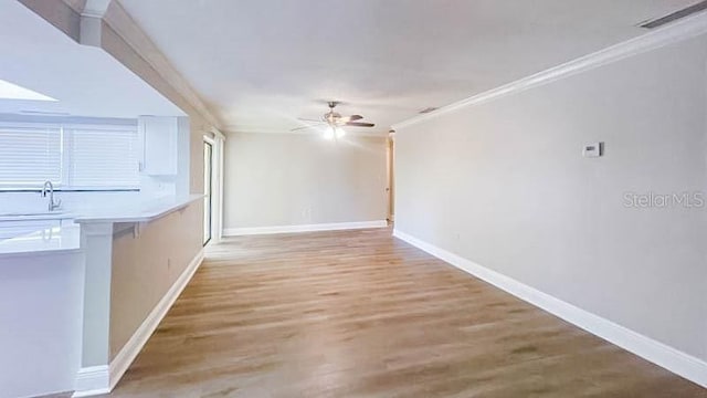 unfurnished living room featuring sink, light hardwood / wood-style flooring, ornamental molding, and ceiling fan