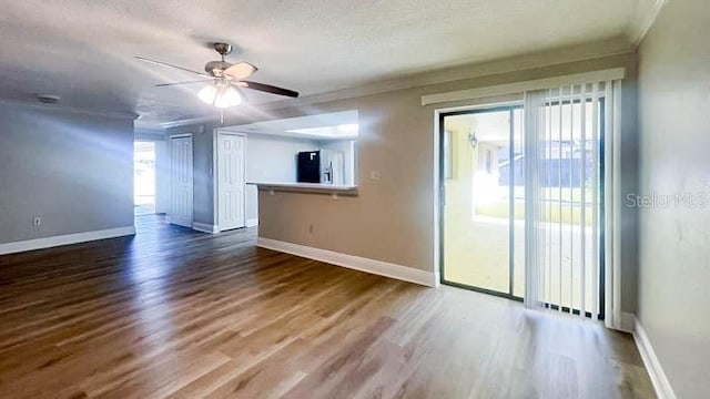 spare room with hardwood / wood-style floors, a textured ceiling, ornamental molding, and ceiling fan