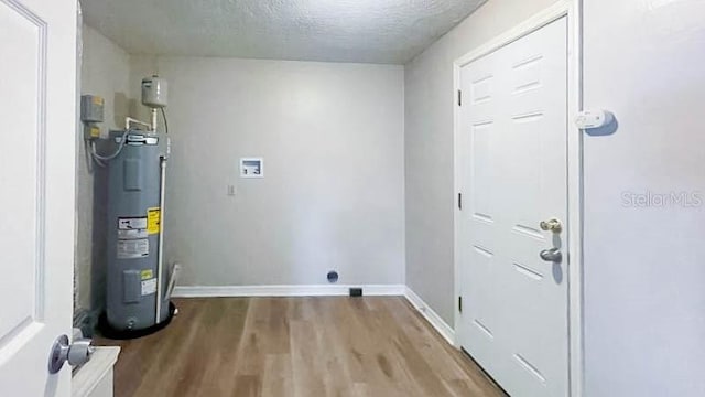 washroom with water heater, hardwood / wood-style flooring, washer hookup, and a textured ceiling