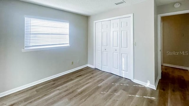 unfurnished bedroom featuring dark wood-type flooring, a closet, and a textured ceiling