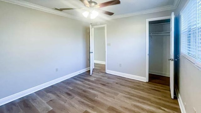 unfurnished bedroom featuring crown molding, dark wood-type flooring, a closet, and ceiling fan