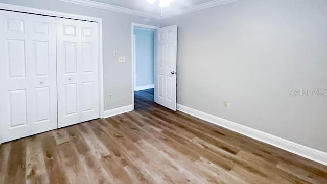 unfurnished bedroom with crown molding, wood-type flooring, and a closet