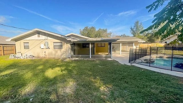 rear view of property with a fenced in pool, a lawn, a sunroom, and a patio