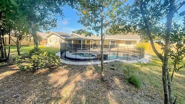 rear view of property featuring a swimming pool with hot tub and a yard