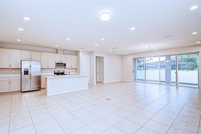 kitchen featuring white cabinetry, light tile patterned floors, a kitchen island with sink, and appliances with stainless steel finishes