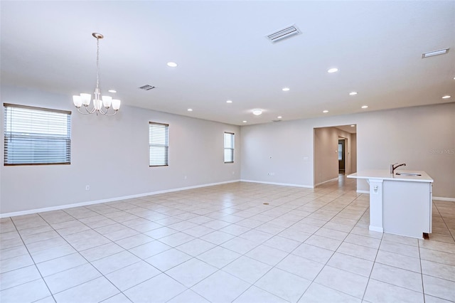 empty room featuring sink, light tile patterned flooring, and a chandelier