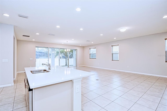 kitchen with light tile patterned floors, sink, and an island with sink