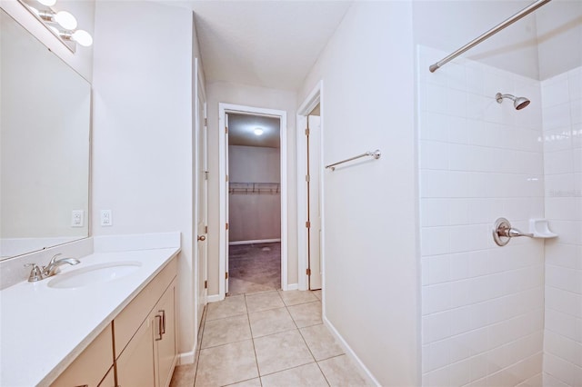 bathroom with tile patterned flooring, vanity, and a tile shower