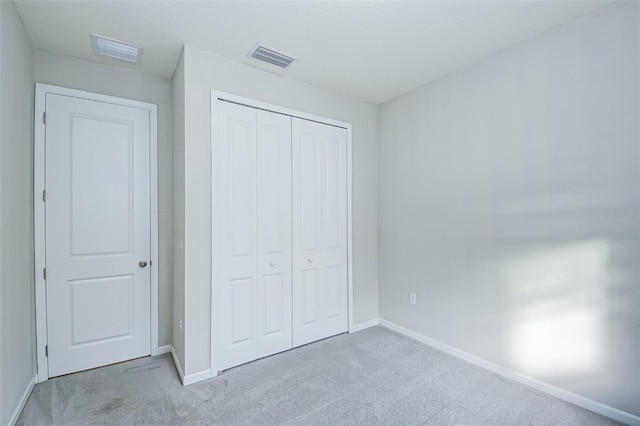 unfurnished bedroom featuring light colored carpet and a closet