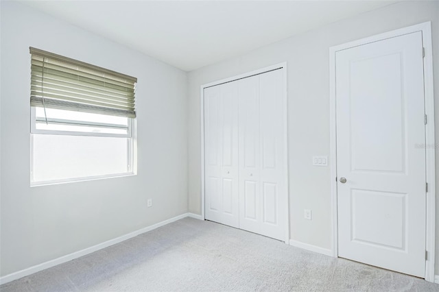 unfurnished bedroom with light carpet and a closet