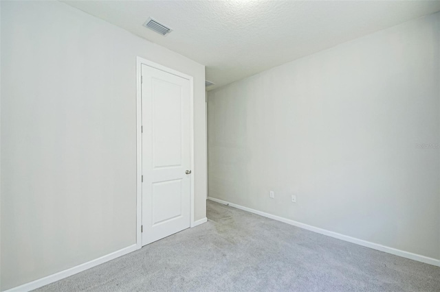 empty room featuring light colored carpet and a textured ceiling