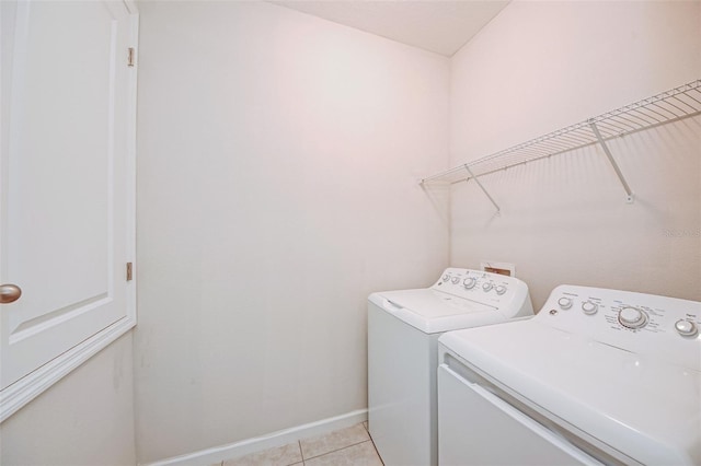 clothes washing area featuring light tile patterned floors and washing machine and clothes dryer