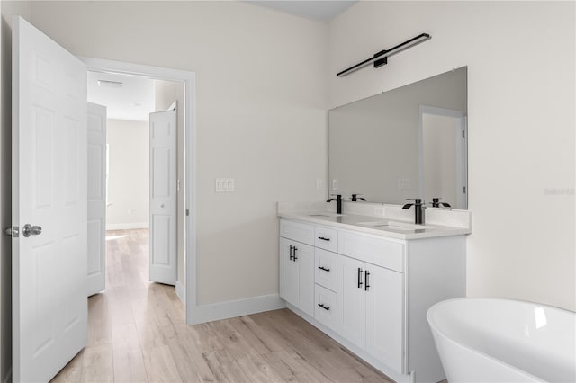 bathroom featuring vanity, wood-type flooring, and a bath