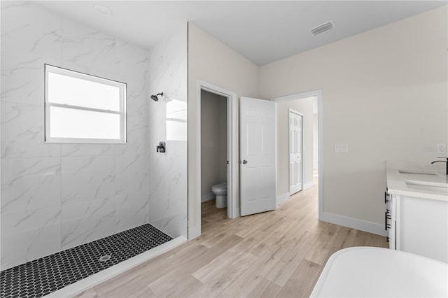 bathroom with a tile shower, toilet, vanity, and hardwood / wood-style flooring