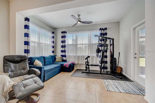 exercise room featuring ceiling fan, light tile patterned floors, and a textured ceiling