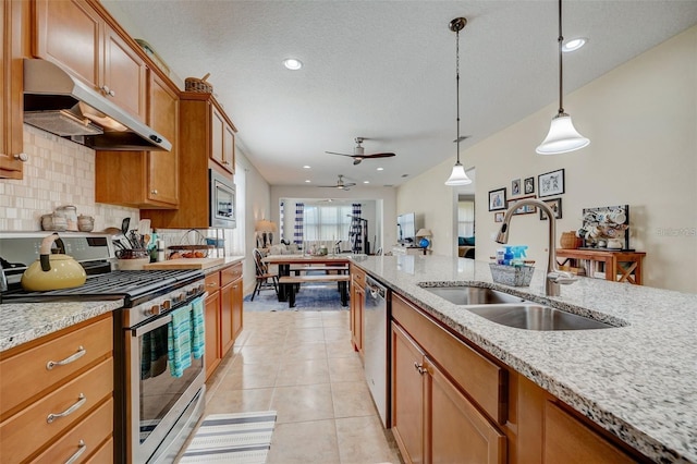 kitchen featuring appliances with stainless steel finishes, light stone counters, ceiling fan, sink, and hanging light fixtures