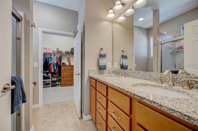 bathroom featuring a shower with door, vanity, and tile patterned flooring