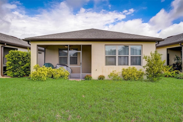 rear view of property featuring ceiling fan and a yard