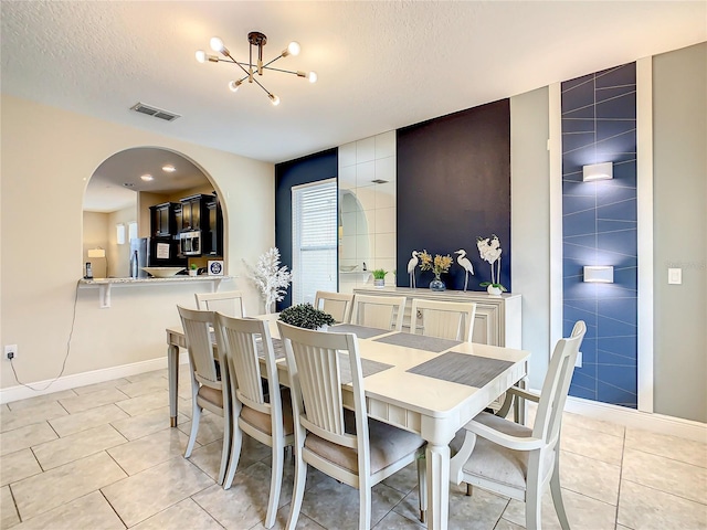 dining area featuring a textured ceiling, an inviting chandelier, tile walls, and light tile patterned flooring