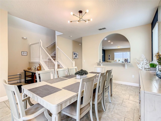 5303 Wildwood Way, Davenport, FL 33837 - dining space featuring a chandelier, stairway, light tile patterned floors, and arched walkways
