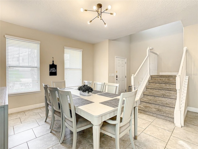 dining room featuring light tile patterned flooring, a textured ceiling, and an inviting chandelier