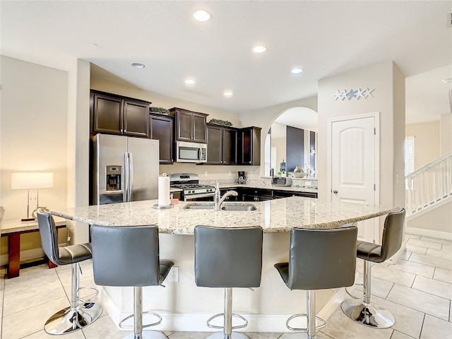 5303 Wildwood Way, Davenport, FL 33837 - kitchen featuring stainless steel appliances, arched walkways, a breakfast bar area, light stone countertops, and recessed lighting