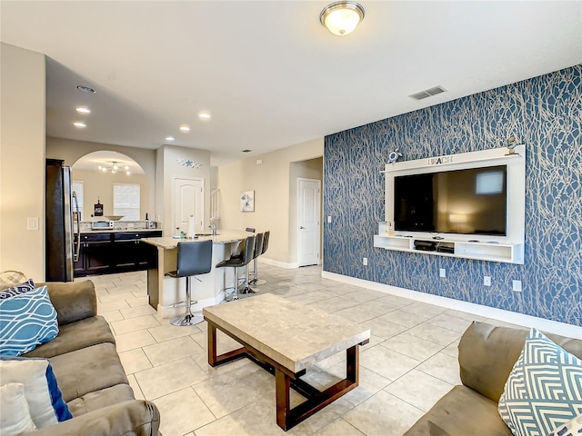 5303 Wildwood Way, Davenport, FL 33837 - living room featuring wallpapered walls, light tile patterned floors, arched walkways, recessed lighting, and an accent wall