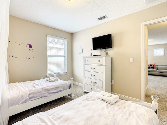 bedroom with dark colored carpet and a textured ceiling