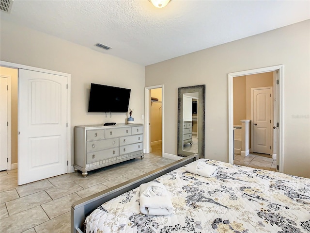 bedroom featuring light tile patterned floors, a textured ceiling, and a closet