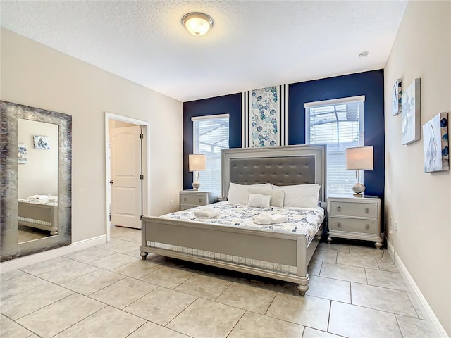 bedroom with light tile patterned floors, a textured ceiling, and multiple windows