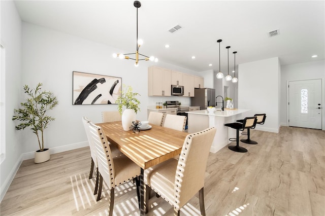 dining space featuring light hardwood / wood-style floors, an inviting chandelier, and sink